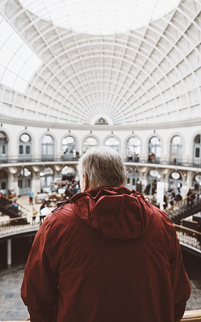 man with red jacket looking at museum architeture